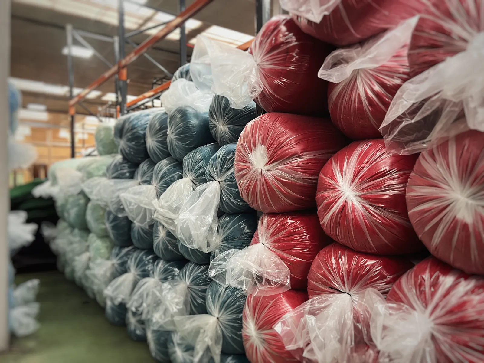 Bagged rolls of coloured pile fabric stacked for despatch